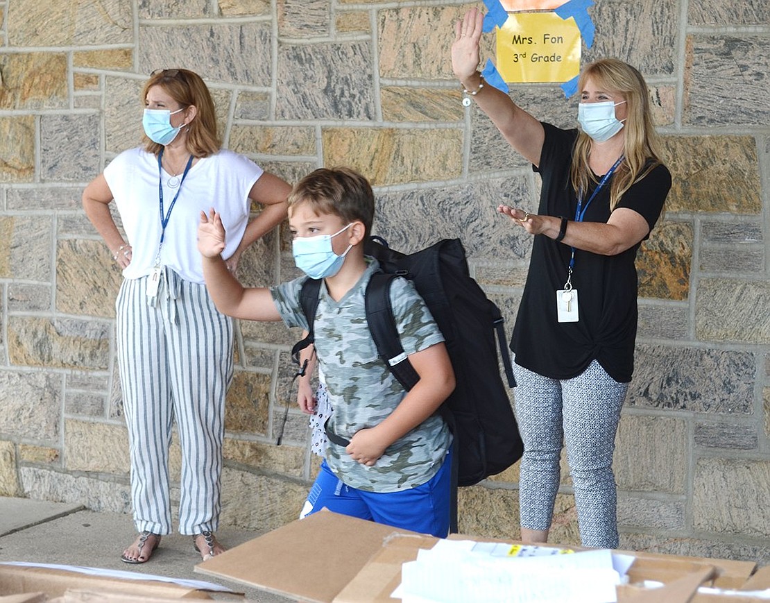 After scanning the crowd for his mother, third-grader Natan Meiri and his teacher Kristi Fon wave hello following a successful first day of school.