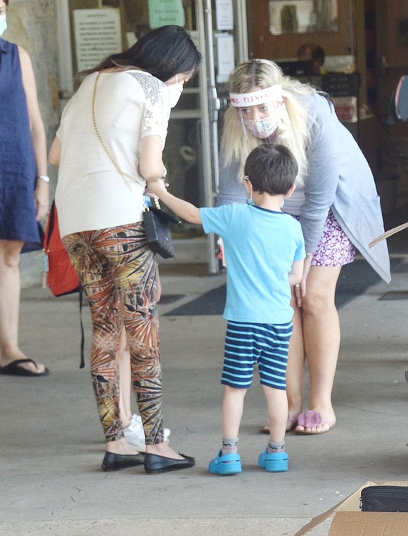 Kindergarten teacher Geri Fisher offers her young student Jared Gordon a toy before they walk into school together.