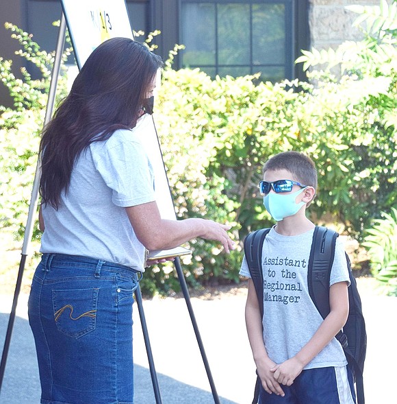 As the afternoon cohort arrives at Ridge Street School, computer aide Kim Froelich helps third-grader Jason Widelec fill out his health screening before heading off to class.