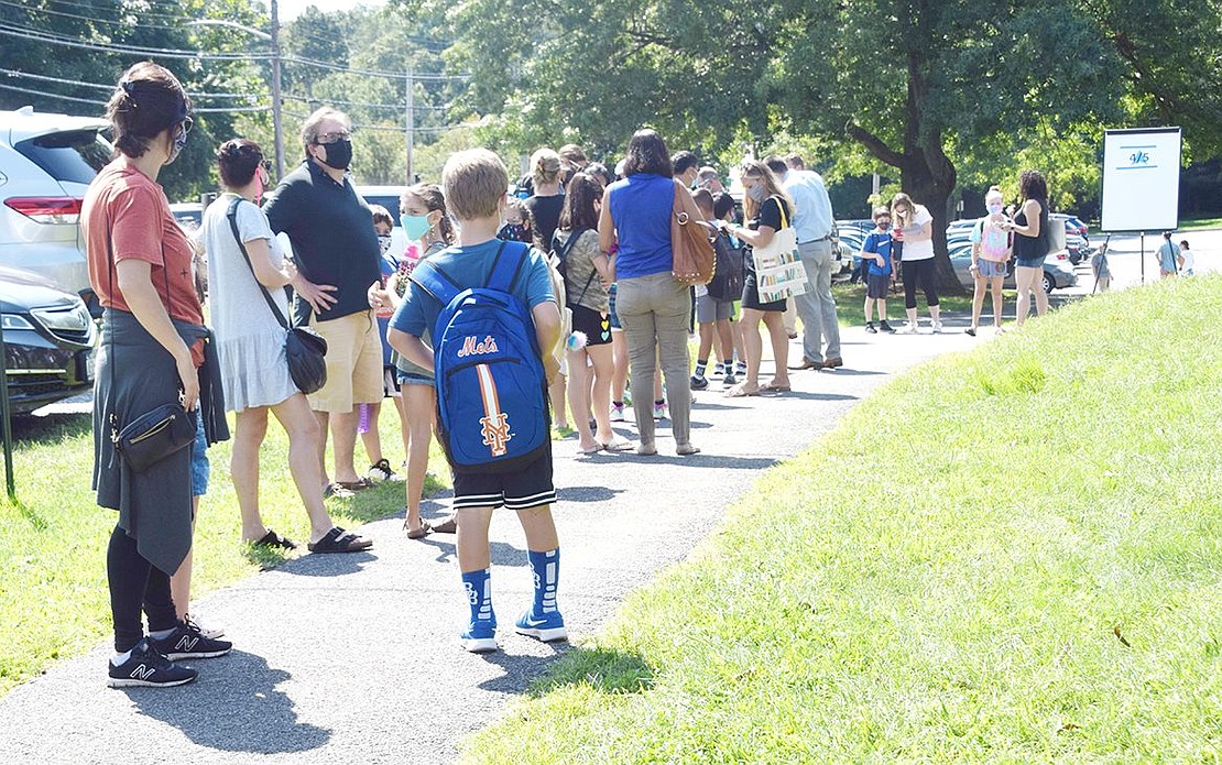 A line forms outside Ridge Street School as parents and students wait to undergo a health screening due to COVID-19 protocols.