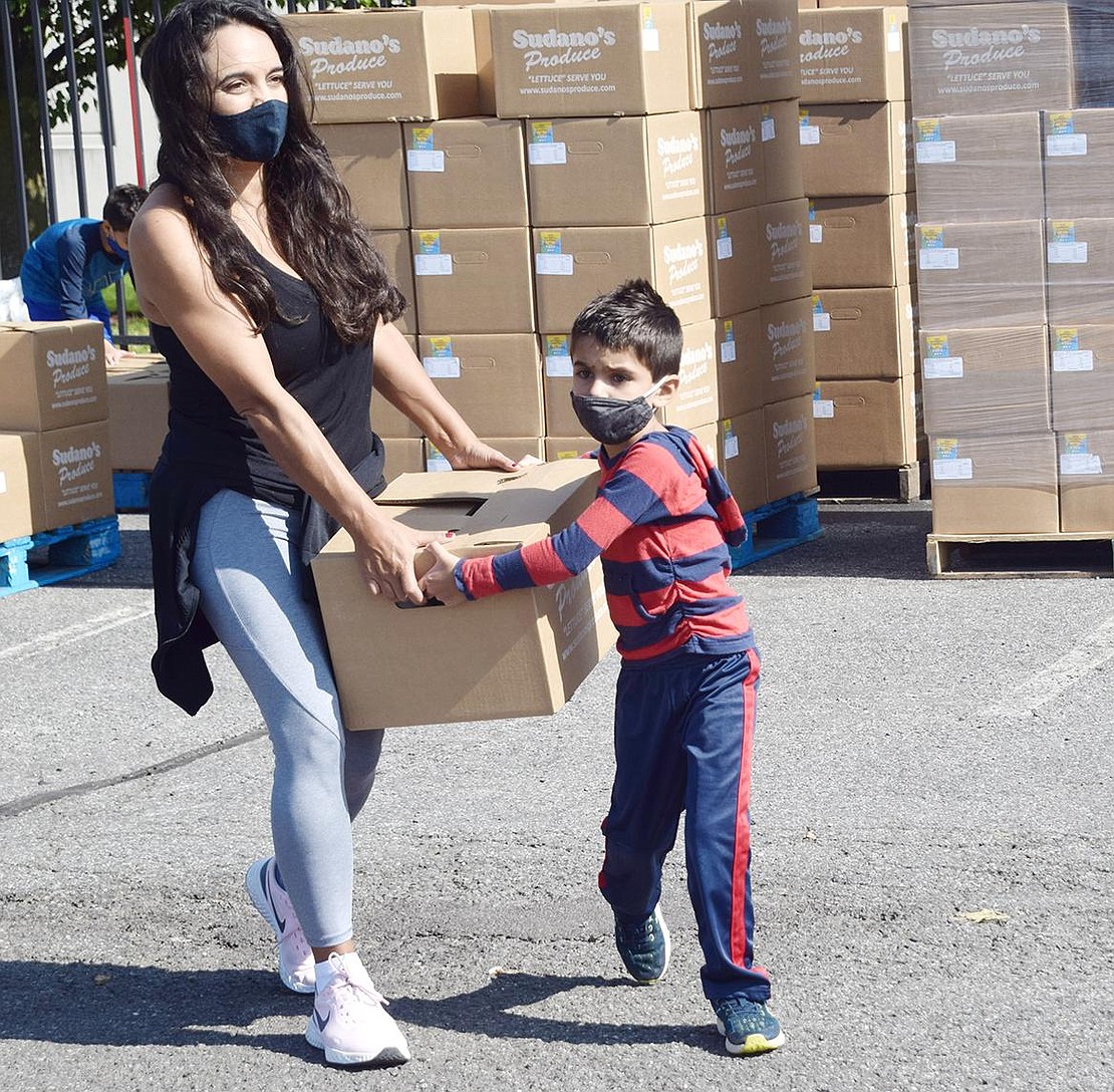 South Salem residents Tatiana Salerno and her son Luke put in a hard day’s work as they jointly carry a box stuffed with fresh produce and food across the Kohl’s Shopping Center parking lot on Wednesday, Sept. 23. Through a USDA grant and collaboration with The Garden of Eden Foundation, Sudano’s Produce and 4MYCITY, Precision Concierge of New York has been distributing food across New York. The Port Chester Police Department teamed up with the organization to bring 58,000 pounds of food to the Village for food pantries, churches and families to utilize.