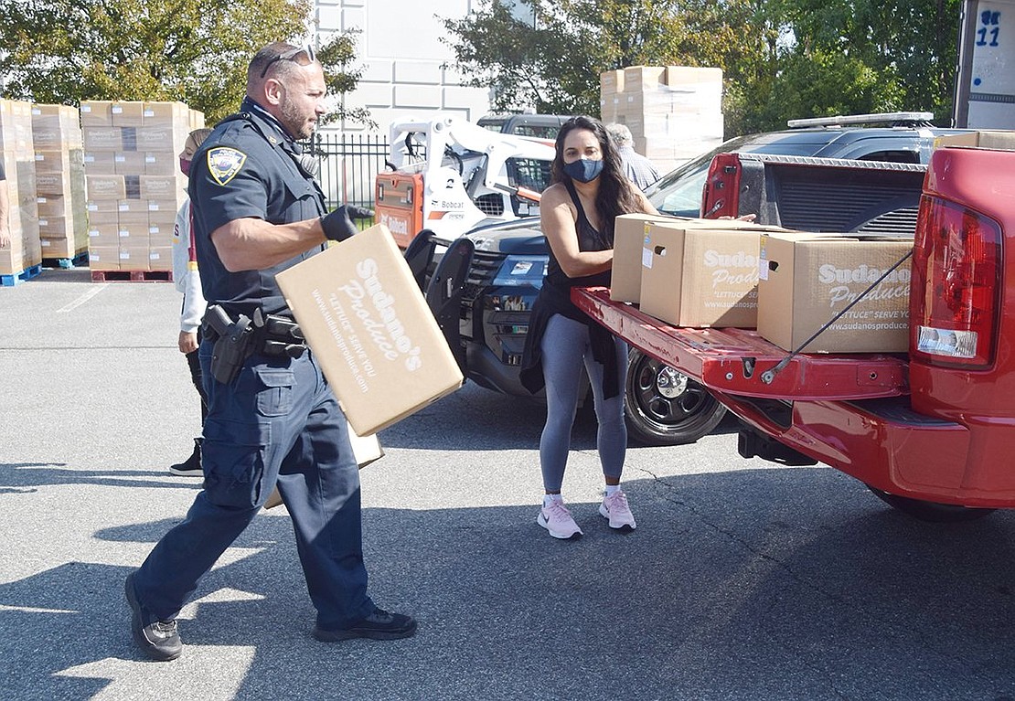 Port Chester Police Officer Nick Stella hauls two boxes of food, each weighing 50 pounds, and places them into the back of a pickup truck. Stella worked with former Mount Vernon police colleague and PCNY volunteer Paul Puccini to bring the initiative to the Village.