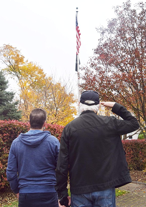 Vietnam veteran Jerry Morano of Rye Brook, accompanied by his son Steven of Port Chester, salutes during the Pledge of Allegiance opening the brief, socially distanced Veterans Day ceremony at Veterans’ Memorial Park, corner of Westchester Avenue and North Regent Street, Wednesday morning, Nov. 11.