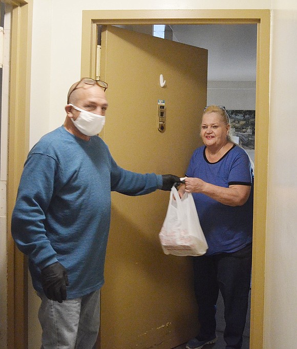 Mike Carpinello, who works for the Port Chester Housing Authority, passes an early Thanksgiving dinner with turkey and all the fixings to Helen Delany at the Terrace Avenue senior apartments on Saturday, Nov. 21. Preparation and delivery of the meals were accomplished by the longtime volunteer group Corporate Outreach aided in this pandemic year by volunteers from other organizations.  