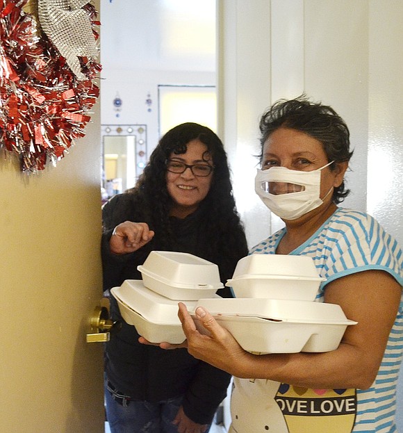 Carol Caldas (left) and Maria Soliz accept Thanksgiving meals from Corporate Outreach volunteers, topped off by pumpkin pie in the small containers. This was the organization’s 34th year providing pre-Thanksgiving warmth to senior citizens in Port Chester. They also delivered to seniors who signed up at the Port Chester Housing Authority owned and operated building on Drew Street.