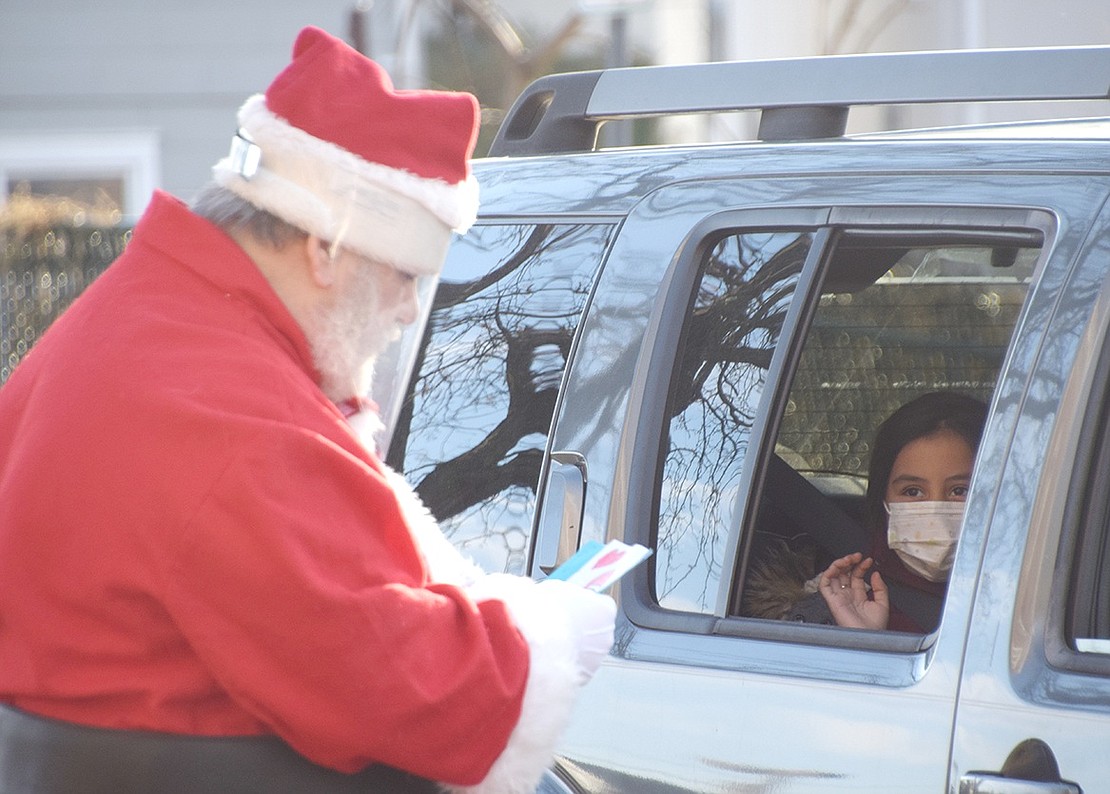 Port Chester resident Loana Hernandez waves at Santa after giving him a letter. Over 750 families pulled up to the Port Chester Senior Community Center in their cars on Sunday, Dec. 13, for a drive-thru event to wave to Mr. Claus and pick up a toy.