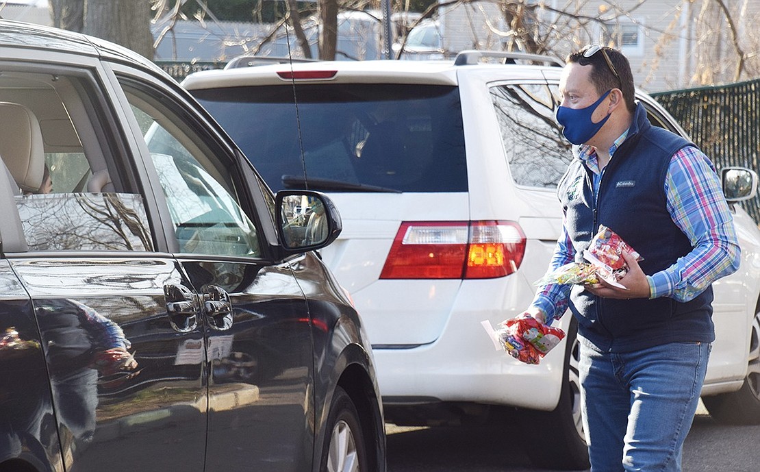 Port Chester Trustee Alex Payan hands out bags of candy to children before they get the chance to meet Mr. Claus.