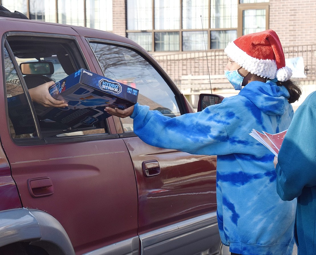 Santa’s helper and Port Chester resident Sky Sams, 12, gives a toy to one of the many families that came to the Port Chester Recreation Department’s Santa drive-thru event.