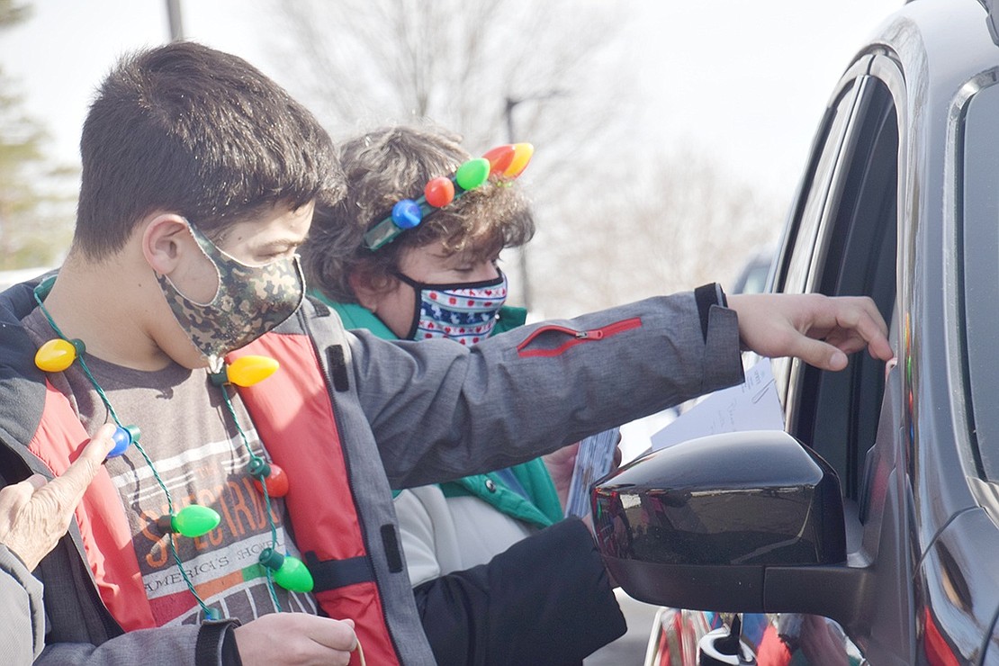 Rye resident Harry Cohen, 13, gives out a candy cane, one of the several goodies participants in SPRYE’S Holiday Drive-Thru received.