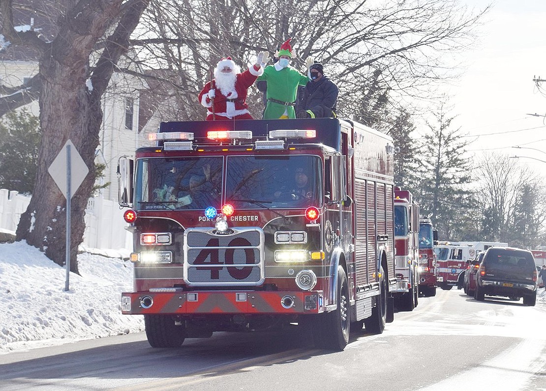 Firetrucks drive up Grace Church Street on their route to take Santa Claus and his friends around the villages.