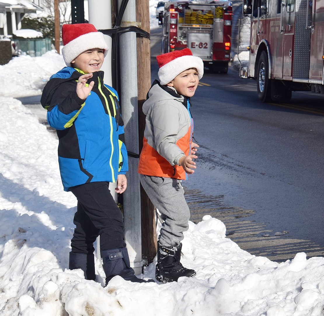 As Santa Claus makes his way down Grace Church Street, Eldredge Street residents Angel Torres (left), 6, and Adrian Torres, 4, wave frantically at him.