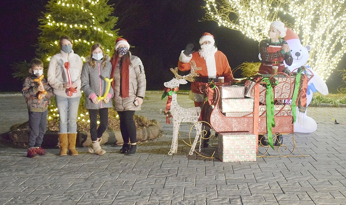 In a socially distanced fashion, Santa Claus waves at the photographer while Mrs. Claus adoringly looks toward Port Chester residents David Laski (left), 7, Angelica Przyslak, 14, Domenica Przyslak, 12, and their mother Aga Przylak.