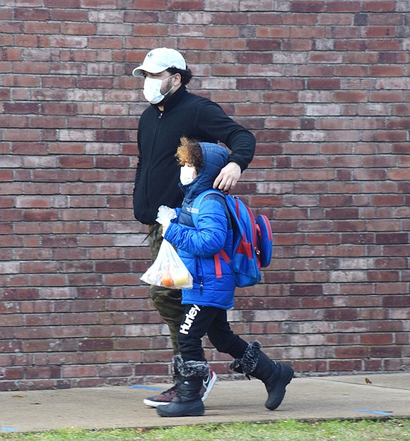 After grabbing his district-provided takeout lunch, John F. Kennedy Elementary School third-grader Rocky Guzmán walks home after class with his father’s arm around his shoulder.