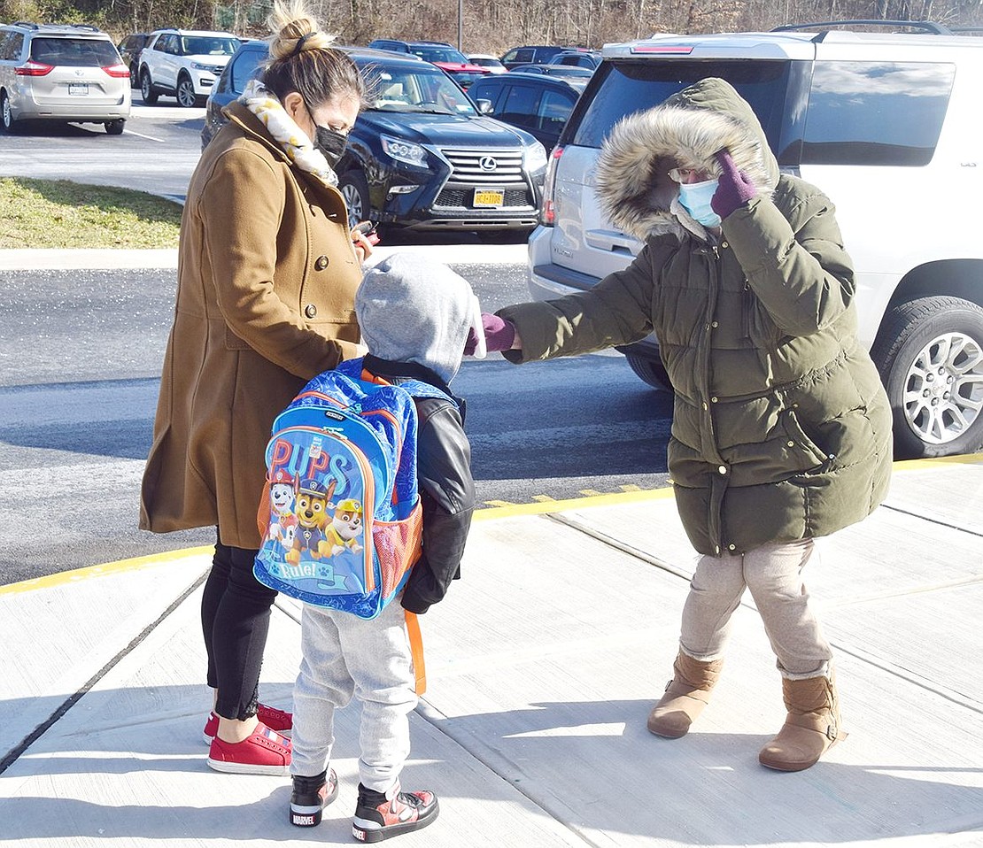 Before he can go inside for his afternoon class, King Street School kindergartner Tyler Castro stops so lunch monitor Jeanette DeLeo can check is temperature.