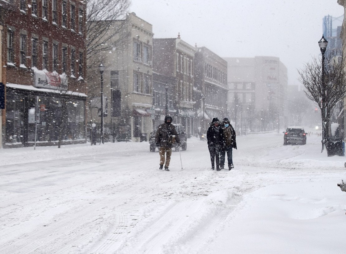 Three men walk in the middle of a mostly-deserted North Main Street during the thick of the storm.