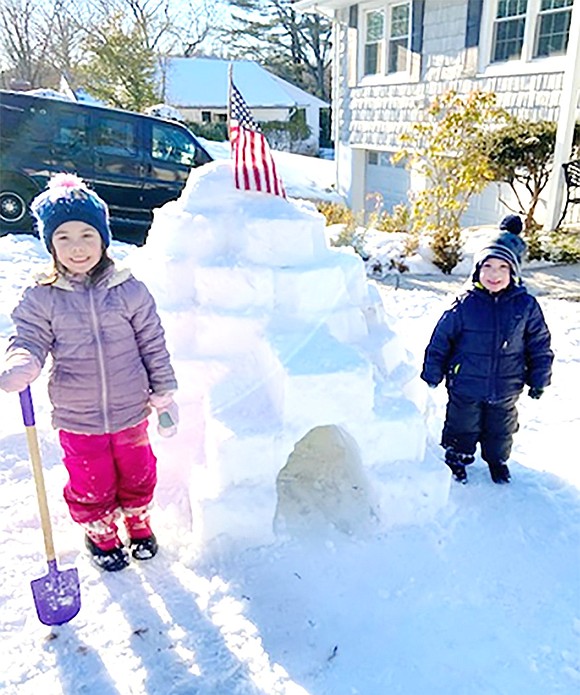 Troy and Taylor Cirillo proudly stand by their igloo at 19 Windingwood Rd. while an American flag planted in the snow waves between them.