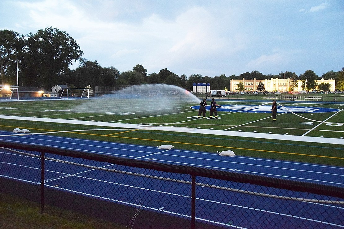 Members of the Port Chester Volunteer Fire Department water down the new artificial turf football field before the fireworks display begins.