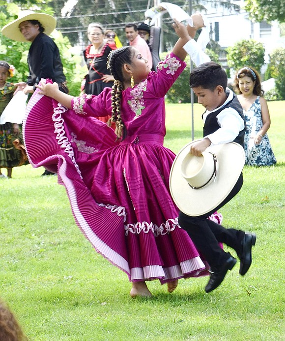 Stamford, Conn. resident Valerie Ruiz, 8, and Norwalk, Conn. resident Liam Tacuri Prada, 8, cross paths on the grass while performing a traditional Peruvian dance at an International Festival at Lyon Park on Sunday, July 18. Organized by the nonprofit Caring & Loving Foundation, the event celebrated cultural diversity, art and folklore while raising money to help Port Chester students.