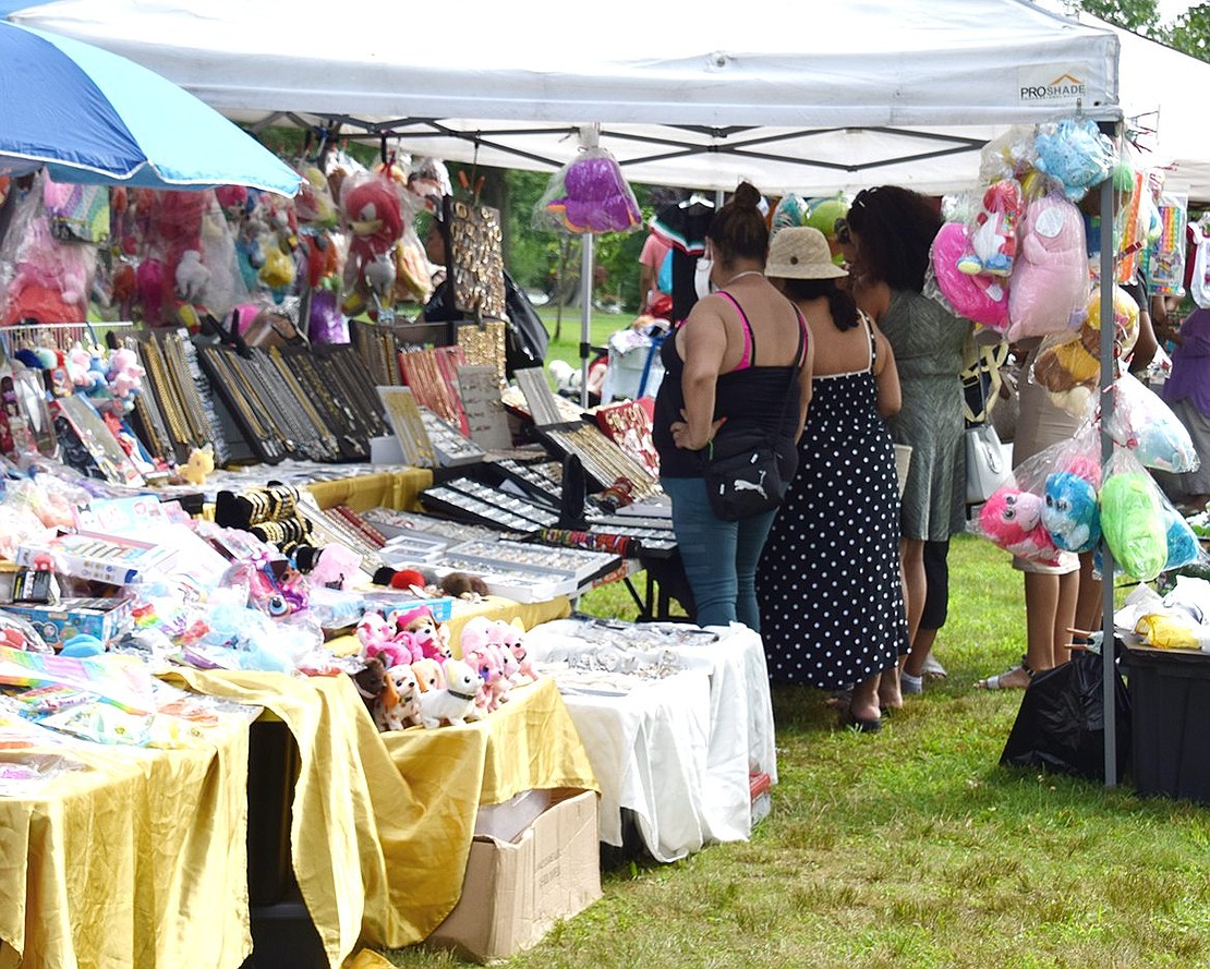 International Festival attendees peruse dolls, art and jewelry for sale at one of the various vendors setting up an elaborate shop at Lyon Park.