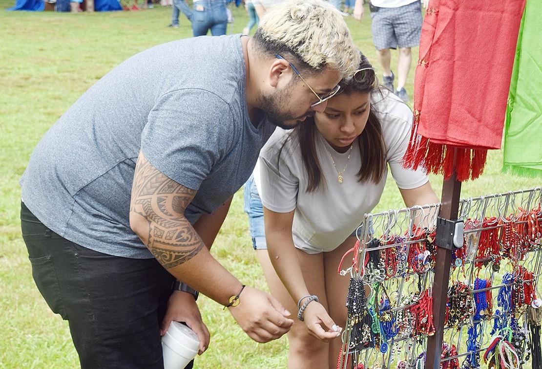 Twenty-nine-year-old Neuton Avenue, Port Chester, resident Alvaro Aparicio helps Leslie Cruz, a 25-year-old Oak Street resident, select the perfect bracelet from an array of vibrant jewelry pieces on display at a pop-up shop.