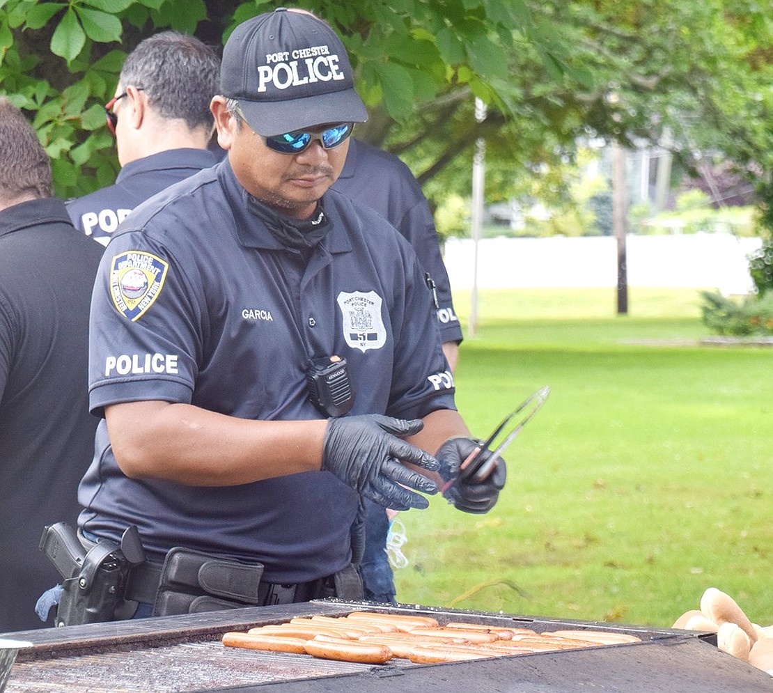 Officer Jeff Garcia mans the grill to serve hot dogs to National Night Out attendees. By the end of the night, the department went through 1,000 hot dogs and just as many Colony Pizza slices, according to Captain Charles Nielsen.