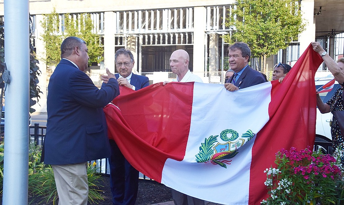 Port Chester Mayor Luis Marino, Rye Town Justice José Castaneda, both born in Peru, Port Chester Trustee Frank Ferrara, County Executive George Latimer and Trustee Joan Grangenois-Thomas hold the Peruvian flag in preparation for its raising on the flagpole in Liberty Square on Wednesday, July 28 to celebrate the bicentennial of Peru’s proclamation of independence from Spain in 1821. State Senator Shelley Mayer and Trustee Bart Didden also participated in the flag raising.