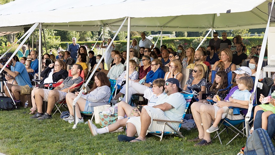 The audience for the July 30 evening performance sits under a tent and spills out onto the lawn on both sides.