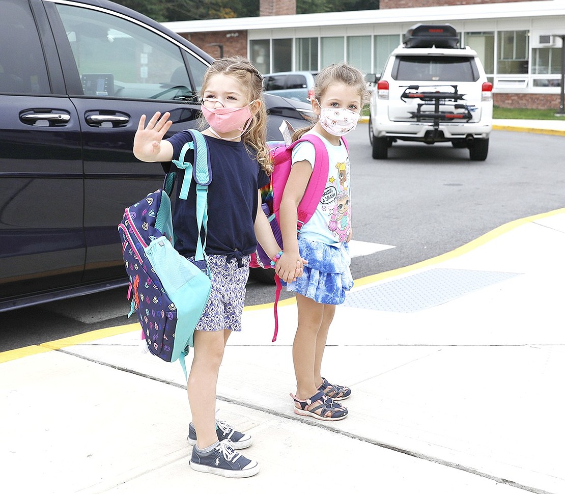 King Street School third-grader Samantha Allen (left) waves to friends while holding hands with her sister, kindergartener Ryan Allen, after being dropped off at school on Wednesday, Sept. 15. Port Chester Schools opened on Thursday, Sept. 9, a week later than planned, due to the flooding caused by Tropical Storm Ida.