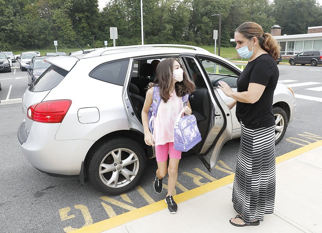 King Street School teacher’s aide Tammy Dominguez opens the car door for fourth-grader Hailey Hodge on Wednesday, Sept. 15.