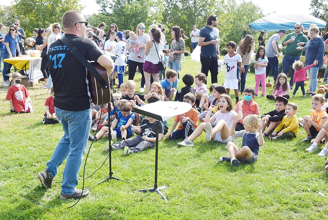 Children gather in front of Greg DiMiceli, the Ridge Street School music teacher, and dance to his songs with the routines they know from class during the Blind Brook PTA plant sale fundraiser at the Middle/High School parking lot on Saturday, Oct. 2. PTA Fundraising co-founder Alicia Scala said DiMiceli had inquired about doing a singalong outside of school hours and she felt the fall fundraiser was the perfect place for it.  