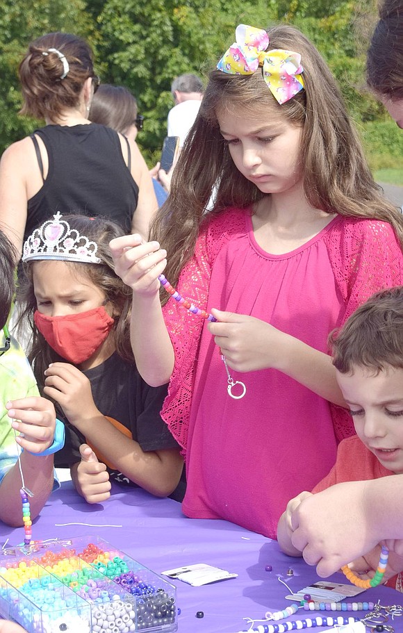 Stringing together a purple and pink bead bracelet to match her outfit and bow, Ridge Street School third-grader Ellie Tapper takes her time at the craft table seriously.