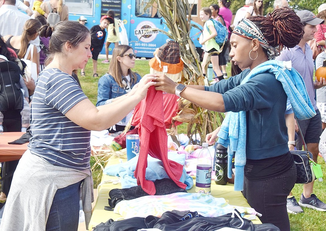 PTA volunteer ToniAnne Rigano (left) helps Latoya Williams find matching Ridge Street School spirit gear for her children by holding up shirts to compare sizes.