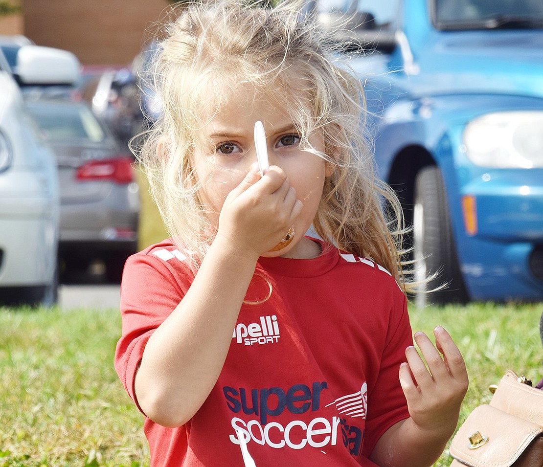 Rye Brook resident Bella Scutero, 3, snacks on her doughnut holes from the Glazed & Confused food truck while listening to music on the grassy hill by the Middle/High School parking lot.