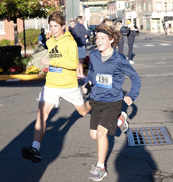 William Jaffee (left) and Daniel Greenspan, both of Rye Brook, are all smiles as they approach the finish line right beside one another on the morning of Sunday, Oct. 17. They are two of almost 400 inaugural participants in the Meals on Main Street fun run called Miles for MOMS in downtown Port Chester, waking up early for an 8 a.m. 1.5-mile course while getting their adrenaline pumping to support holiday meals for people facing food insecurity.