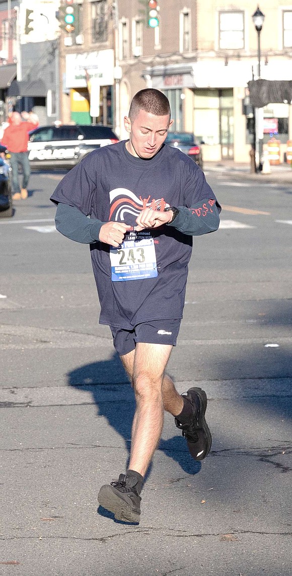 First place men’s winner John Barrett checks his time on his wristwatch, just feet away from the finish line in the marina parking lot. The Rye Brook resident finished with a time of 8 minutes and 42.1 seconds.