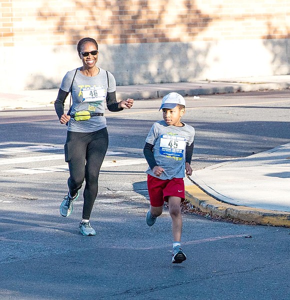 Veronique Ferguson (left) sports sunglasses while running behind Ethan Ferguson, both Harrison residents, as the sun comes out. 