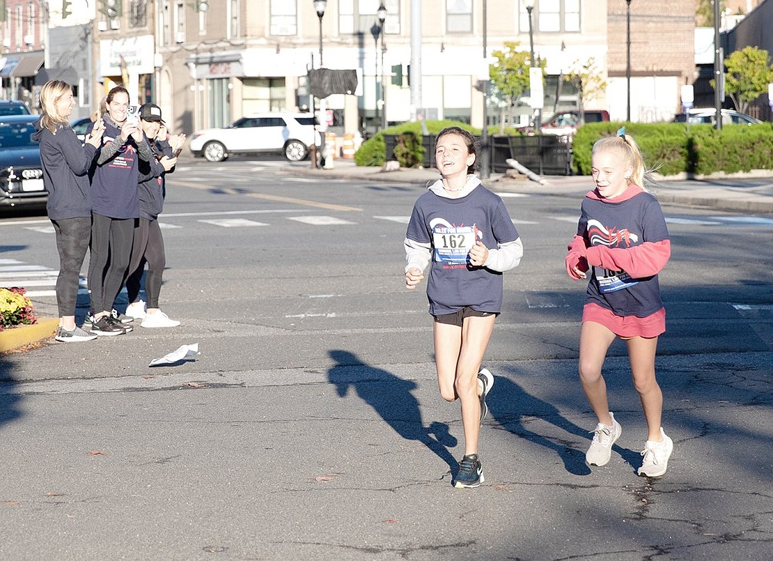 Spectators cheer as Reese (left) and Richie Morrow, both Rye residents, push through their final stride together.