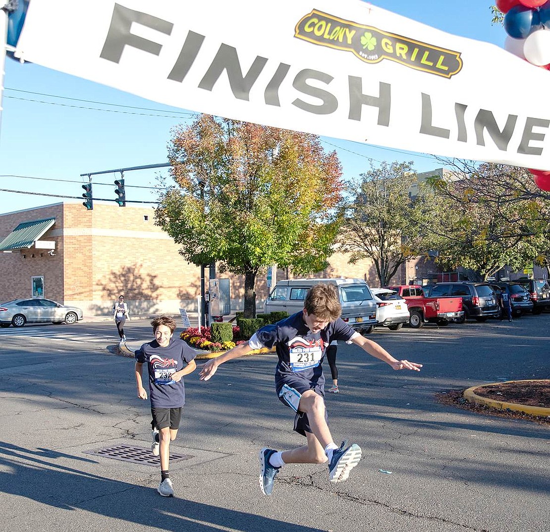 Luke Alaimo (right) jumps in the air as he finishes the race in the Port Chester marina parking lot, with Harrison Delaney right behind him. Both runners are from Rye.