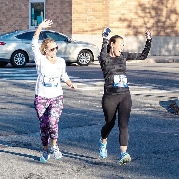 Rye resident Laura Linehan (left) and Vanessa Gunther, of Bronxville, throw their arms in the air as they run together toward the finish line.