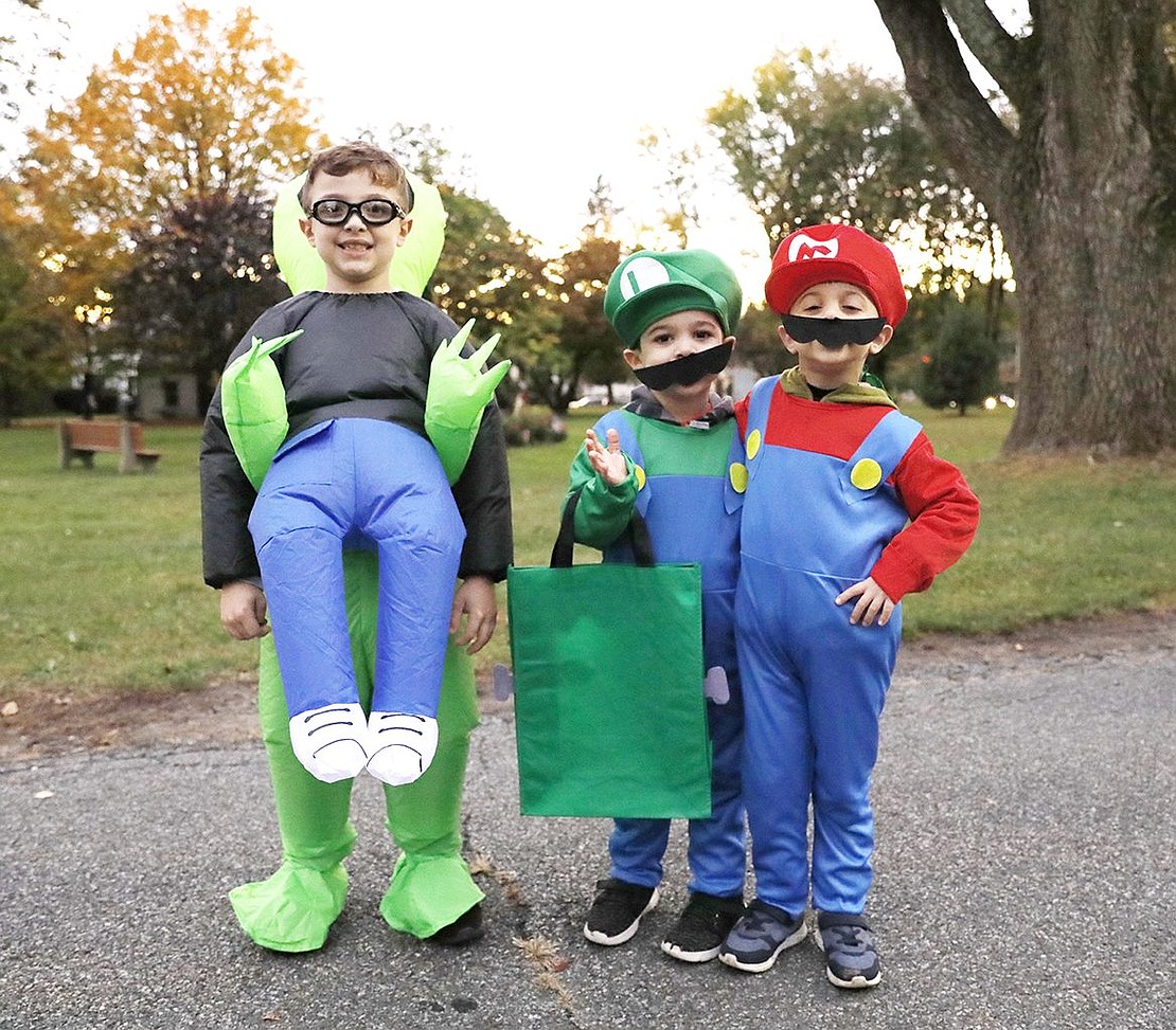 Park Avenue Elementary School fourth-grader Tyler Varbero (left), dressed as an alien abducting a child, and his brothers, Little Friends preschooler Evan and Park Avenue kindergartner Luke, dressed as Luigi and Mario, wait in line for treats.