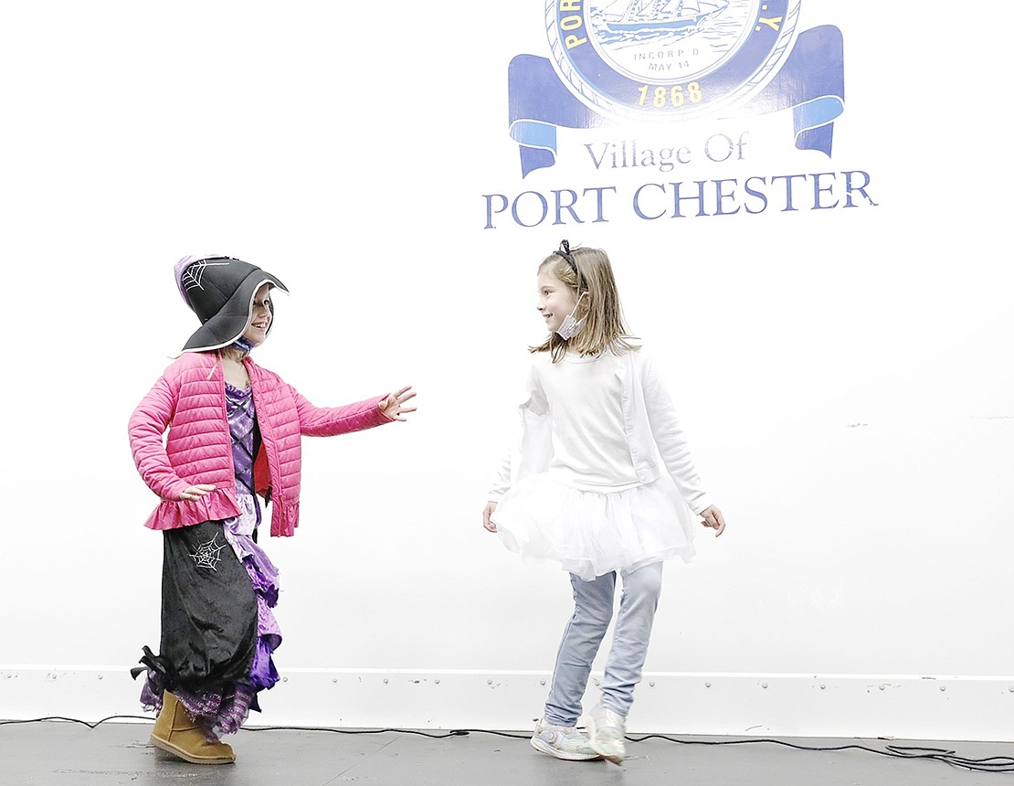 Both first-graders at the Resurrection Grammar School in Rye, Maddie Hering, dressed as a witch, and Penelope Megliacca, dressed as a cat-ghost, dance together on stage.