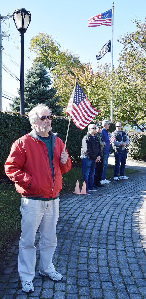 Peter Feinman of Lyon Farm Village, a member of the Port Chester Historical Society, waves an American flag at the sparsely attended ceremony.