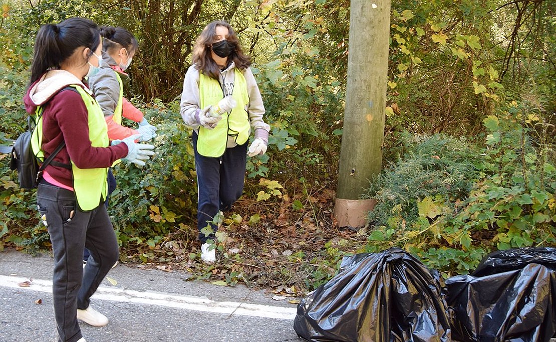 About 30 members of the Port Chester High School Key Club cleaned up trash along a closed off portion of Bowman Avenue in Rye Brook, including freshman Lena Zheng, junior Amy Zheng and junior Natalie Pinto, the latter emerging from the woods with an empty bottle.