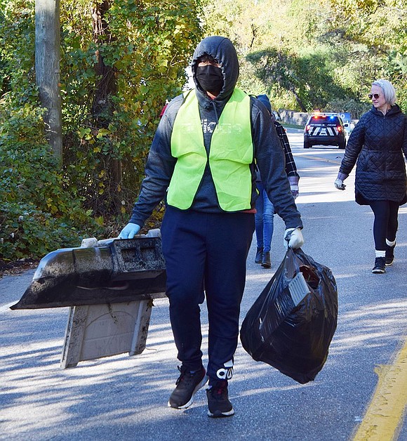 Port Chester High School sophomore Bryan Rivera carries a bag full of trash plus two large pieces of plastic he found in the woods along Bowman Avenue. All the debris picked up along Bowman, including a full bottle of water to fit a dispenser and a toilet, weighed 607 pounds.