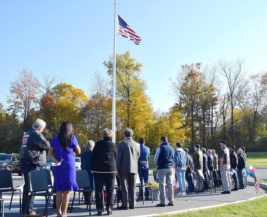School officials, elected officials and honored veterans face the American flag at King Street School in silence while high school band director Mike Miceli plays the National Anthem on the trumpet.