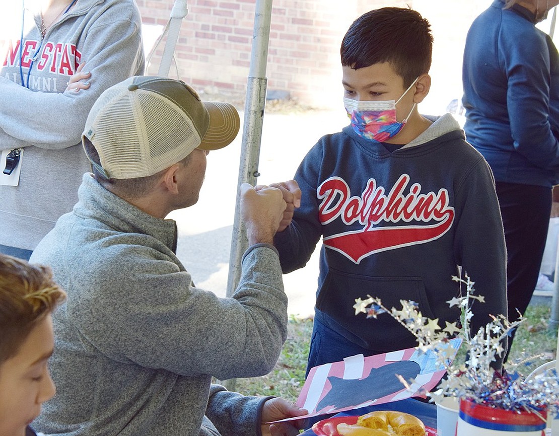 Trevor Buchanan, a U.S. Navy Riverine veteran who just came home from deployment four months ago, offers Oscar Martinez a fist bump after the King Street School fourth-grader gave him a handmade thank you note and picture during the appreciation breakfast after the ceremony.