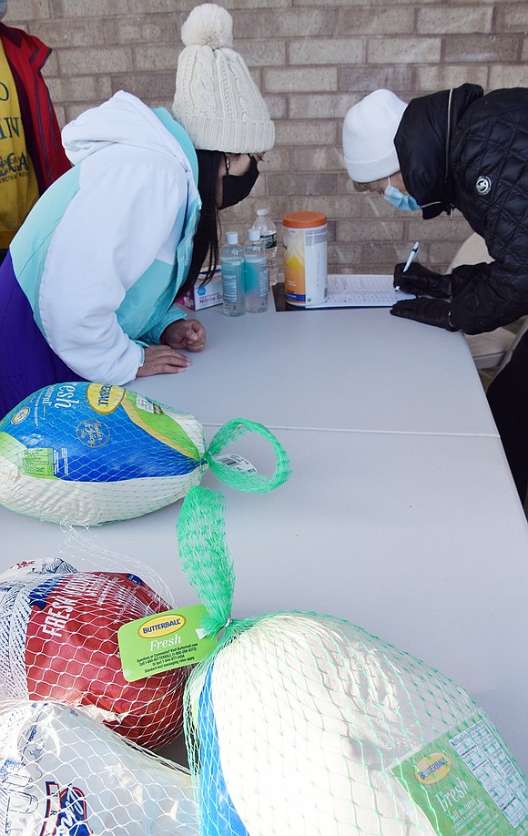 Latecomer Rosa Guallasaca of Port Chester gives her name and contact information to volunteer Vera Wethington before receiving a turkey.