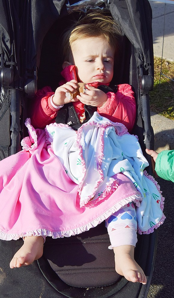 Piper Spinelli, 22 months, of College Avenue munches on a doughnut. She wasn’t bothered a bit by the cold and refused to put on shoes, said her mom.