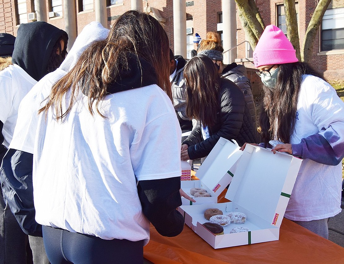 Port Chester High School Key Club members, including senior Dyana Sandoval at the end of the line, dish out doughnuts to participants before the race.