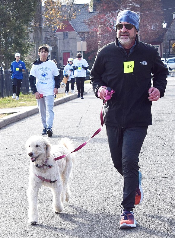 David Hartman of Argyle Road trots along with his dog Scout. Scout and Hartman’s previous dog have been accompanying him on the Turkey Trot every year since 2014.